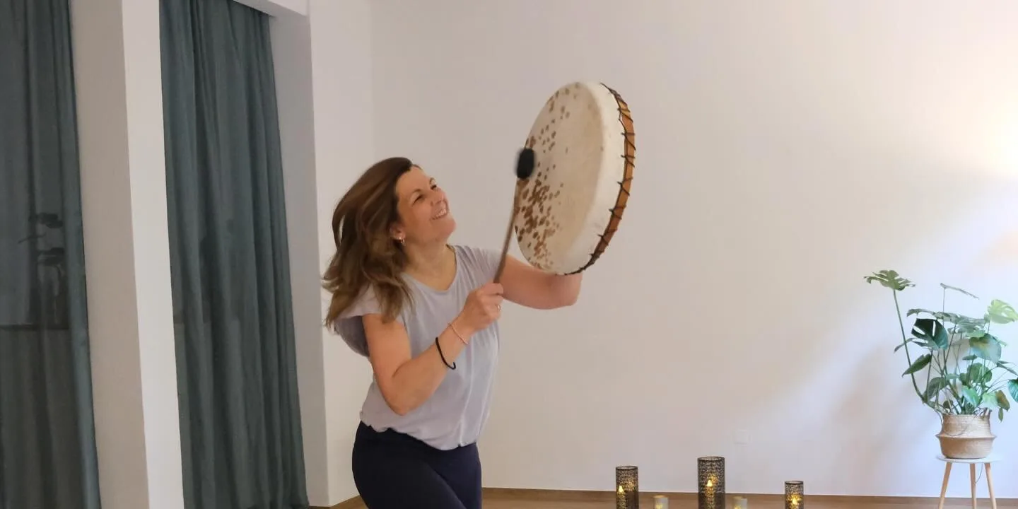 Lisa Wolk spielt lachend die Rahmentrommel im Yogaraum